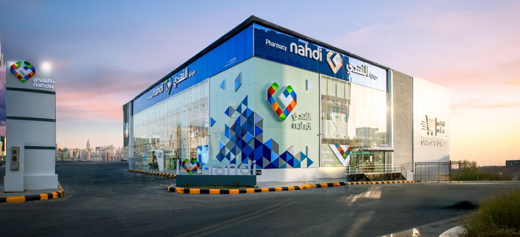 Nahdi pharmacy building with bilingual signage and its multicoloured heart logo.